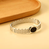 Woven mesh bracelet with black round oil drops.