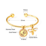 Gold colored hard bracelet with flower and butterfly charm