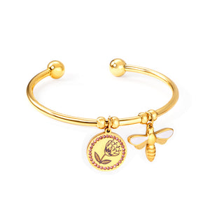 Gold colored hard bracelet with flower and butterfly charm