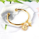 Gold colored hard bracelet with flower and butterfly charm