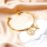 Gold colored hard bracelet with flower and butterfly charm