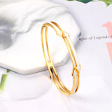 Gold colored hard bracelet with directional arrows with oil dripping in the center white color