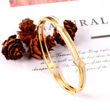 Gold colored hard bracelet with directional arrows with oil dripping in the center white color