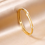 Gold colored hard bracelet with directional arrows with oil dripping in the center white color