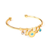 Gold bangle with two diamonds of different colors and a charm with a scallop on the door of the discus.