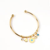 Gold bangle with two diamonds of different colors and a charm with a scallop on the door of the discus.