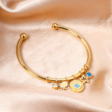 Gold bangle with two diamonds of different colors and a charm with a scallop on the door of the discus.